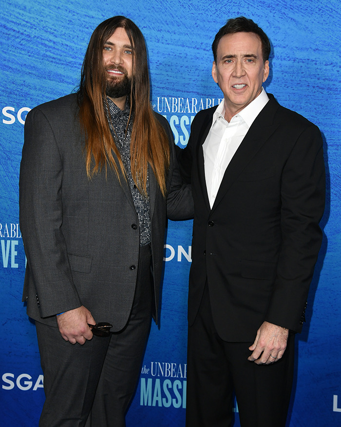 Nicolas Cage and Weston Coppola Cage in suits at a blue-themed event, posing for a photo. Nicolas Cage and Weston Coppola Cage in suits at a blue-themed event, posing for a photo.