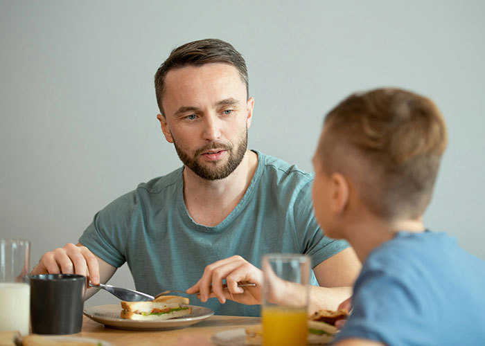 Parenting coach talking calmly to a child over lunch, highlighting reasons to avoid yelling. Parenting coach talking calmly to a child over lunch, highlighting reasons to avoid yelling.