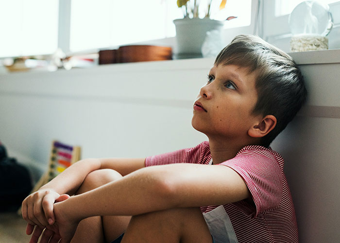 Child sitting thoughtfully in a sunlit room, highlighting parenting coach advice on stopping yelling at kids. Child sitting thoughtfully in a sunlit room, highlighting parenting coach advice on stopping yelling at kids.