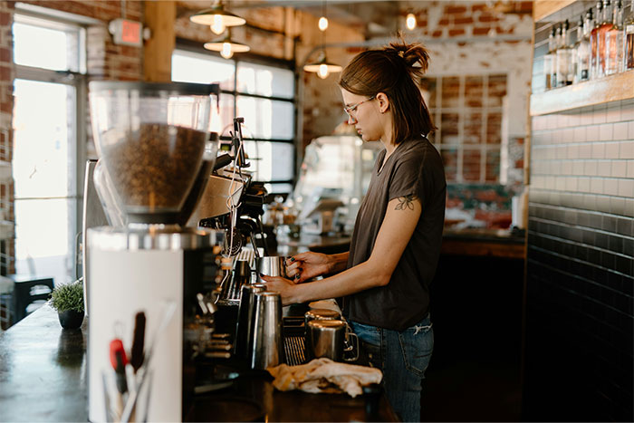 Barista preparing coffee in a cafe setting, highlighting the pay it forward culture in customer service. Barista preparing coffee in a cafe setting, highlighting the pay it forward culture in customer service.