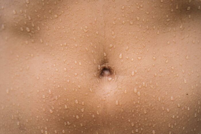Close-up of a belly button with water droplets, emphasizing common hygiene habits to prevent stinky body issues.