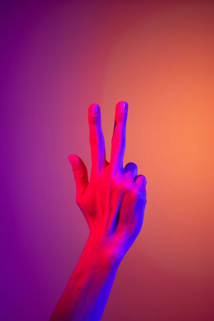 A hand showing three fingers against a colorful gradient background, symbolizing the superstition of bad luck coming in threes.