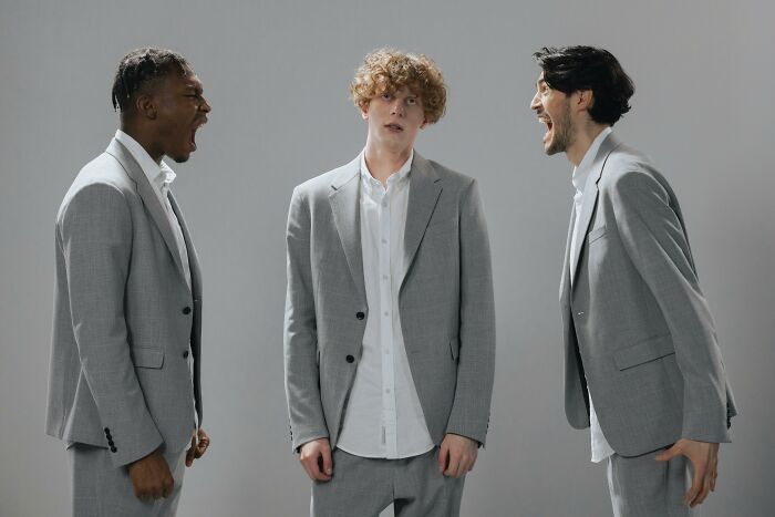 Three men in gray suits, with two shouting, illustrating work-struggles and office tension.