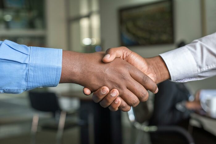 Two people shaking hands in an office, illustrating a common social rule people often ignore.