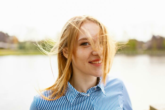 Smiling woman outside wearing a striped shirt with windblown hair, illustrating genetic blessings.