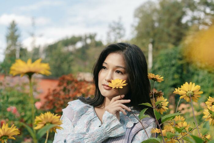 Woman enjoying flowers in a garden, reflecting genetic blessings amidst nature's beauty.