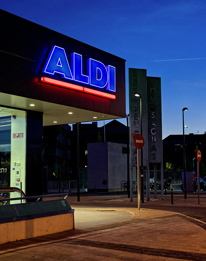 Aldi store exterior at night with bright signage. Aldi store exterior at night with bright signage.