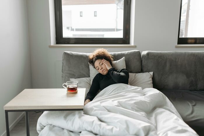 Person resting on a couch, showing the balance of genetic blessings and weaknesses with a cup of tea on a small table.