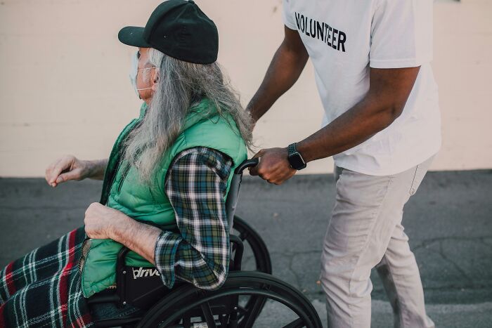 Volunteer assisting person in wheelchair, showcasing brilliant-life-hacks for mobility and support.