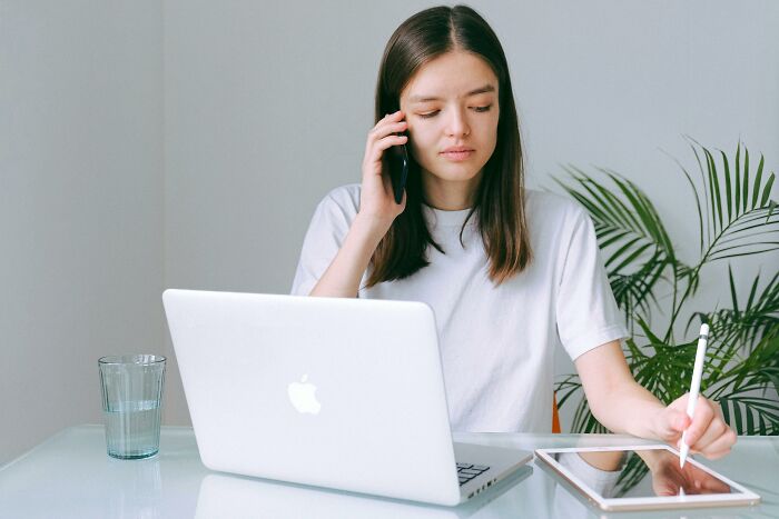 Person multitasking with phone and tablet at desk, illustrating ignored social rules.