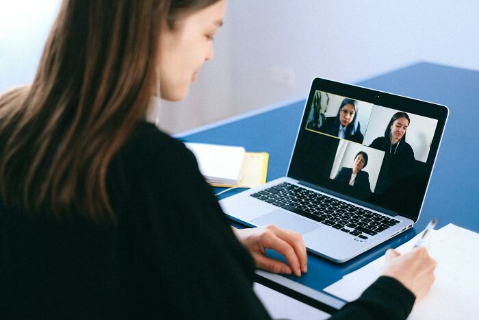 Person in a virtual meeting on a laptop, possibly sharing jokes about office life.