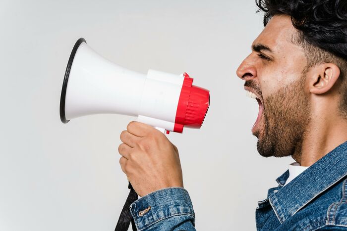 Person yelling into a megaphone, expressing a lack of communication skills in a work setting.