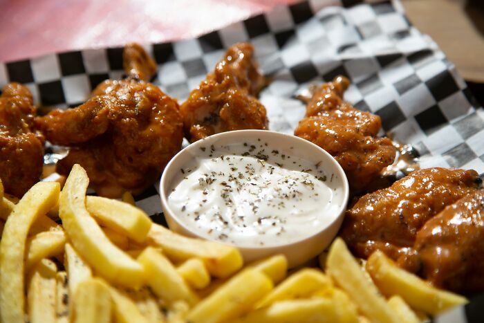 Plate of buffalo wings and fries with ranch dipping sauce, showcasing multipurpose dining options.