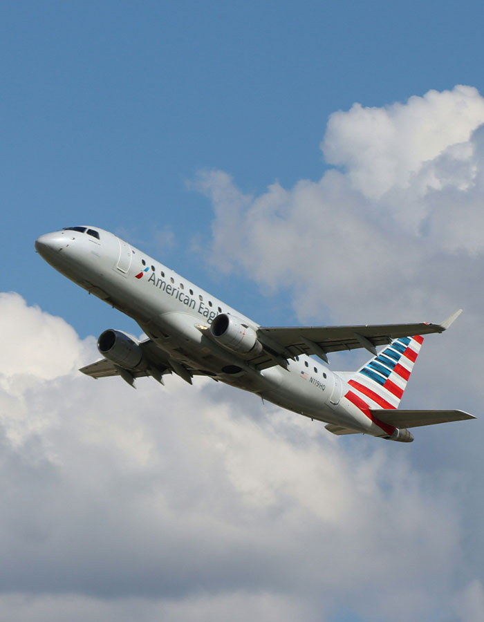 American Airlines plane flying under a blue sky with clouds. American Airlines plane flying under a blue sky with clouds.