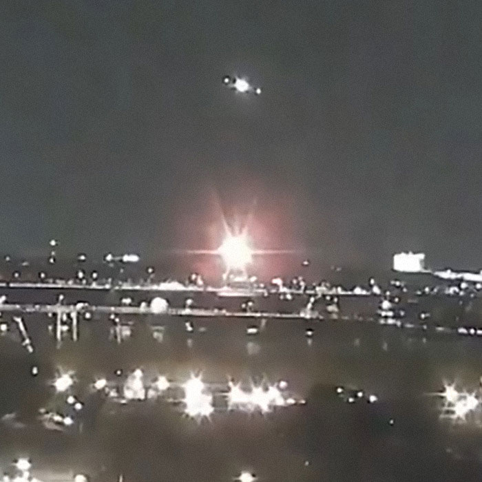 Nighttime scene with a helicopter flying over a city, lights illuminating the skyline amidst a Black Hawk drill. Nighttime scene with a helicopter flying over a city, lights illuminating the skyline amidst a Black Hawk drill.
