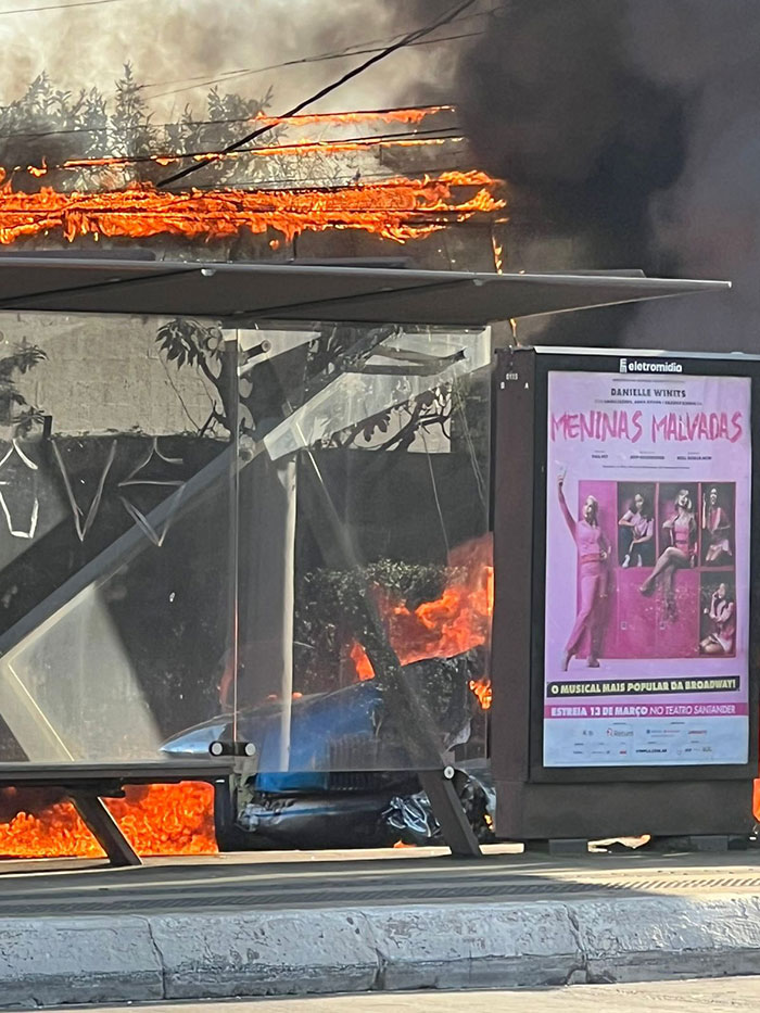 Bus shelter engulfed in flames after aviation disaster with plane crash nearby. Bus shelter engulfed in flames after aviation disaster with plane crash nearby.