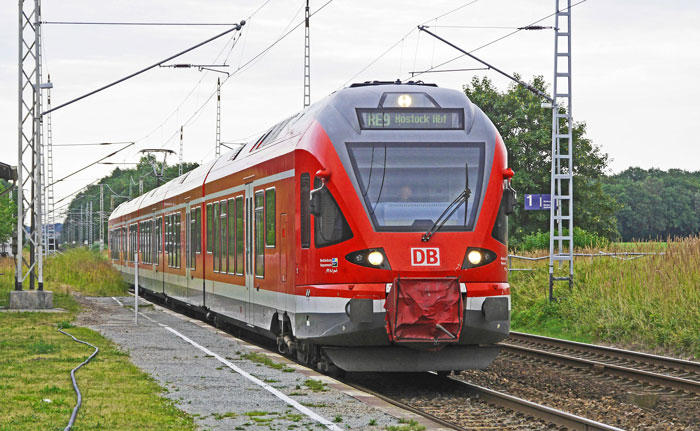 Red train on a railway track surrounded by greenery, under a cloudy sky. Red train on a railway track surrounded by greenery, under a cloudy sky.