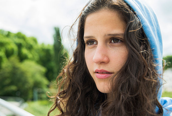 Teen in a blue hoodie outdoors, with a thoughtful expression, dealing with a challenging situation. Teen in a blue hoodie outdoors, with a thoughtful expression, dealing with a challenging situation.