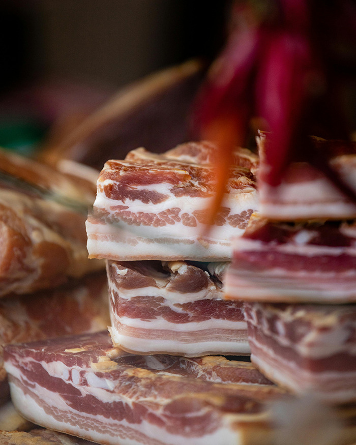 Slices of bacon stacked in a display, highlighting marbled fat and meat texture. Slices of bacon stacked in a display, highlighting marbled fat and meat texture.
