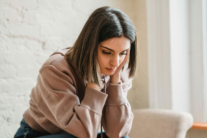 Distraught restaurant worker sitting alone, wearing a brown sweater, contemplating an unexpected work situation. Distraught restaurant worker sitting alone, wearing a brown sweater, contemplating an unexpected work situation.