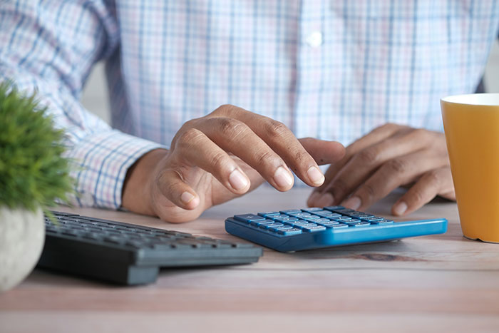 Hands using calculator on a desk with a cup, discussing rent payment issues. Hands using calculator on a desk with a cup, discussing rent payment issues.