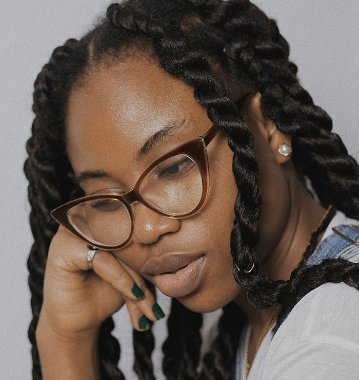 Young woman with glasses and braided hair, contemplating a decision about family and rent. Young woman with glasses and braided hair, contemplating a decision about family and rent.