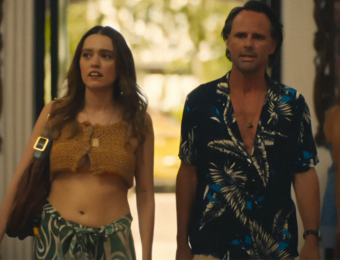 A woman in a crochet top and a man in a floral shirt walking inside, representing a scene from 'The White Lotus'. A woman in a crochet top and a man in a floral shirt walking inside, representing a scene from 'The White Lotus'.