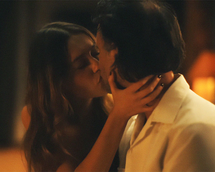 A couple sharing an intimate kiss, highlighting the debate on intimacy coordinators in a dimly lit setting. A couple sharing an intimate kiss, highlighting the debate on intimacy coordinators in a dimly lit setting.