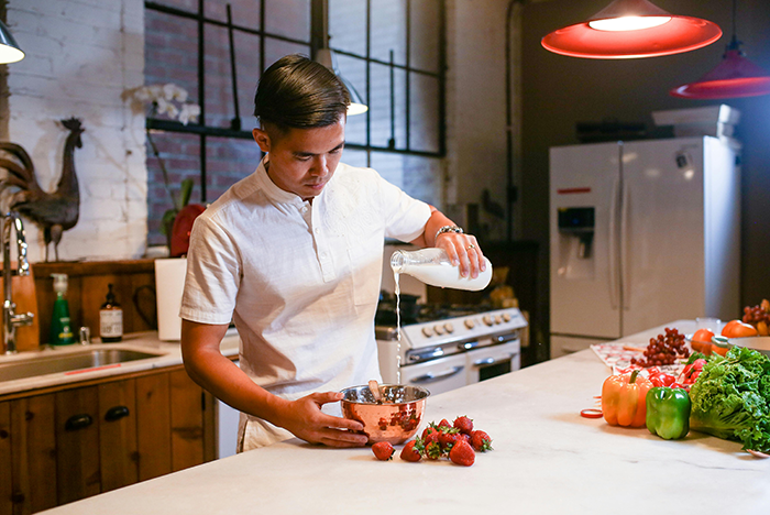 Man cooking in a kitchen, preparing food with fresh ingredients on the counter. Man cooking in a kitchen, preparing food with fresh ingredients on the counter.