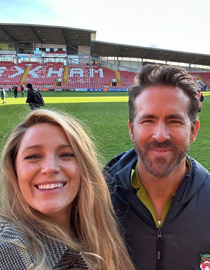 Selfie of a smiling woman with Ryan Reynolds at a stadium, both dressed casually, with empty stands in the background. Selfie of a smiling woman with Ryan Reynolds at a stadium, both dressed casually, with empty stands in the background.