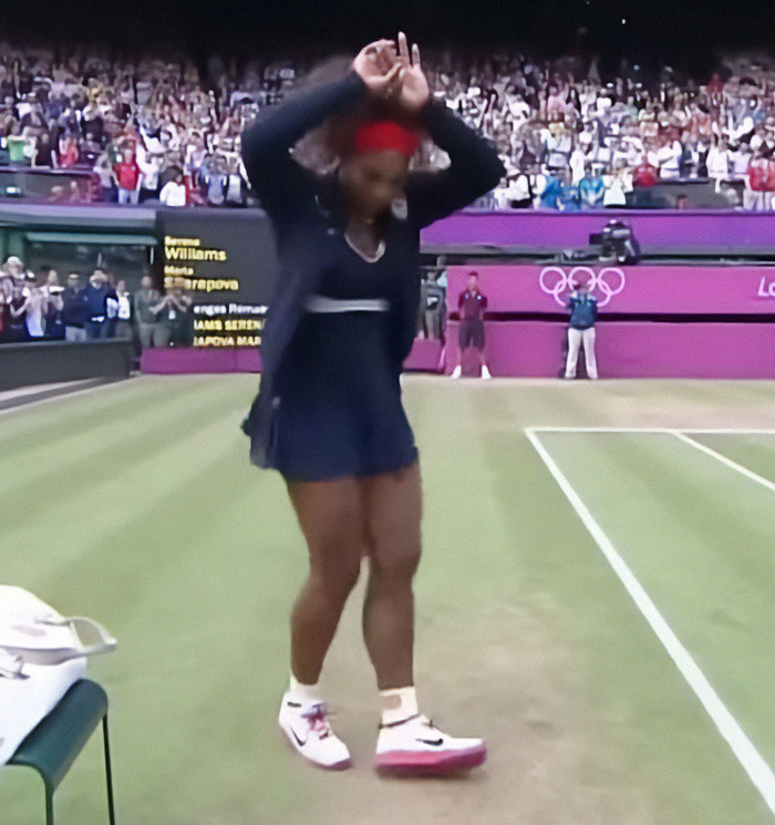 Serena Williams performing a dance on a tennis court, with an audience in the background. Serena Williams performing a dance on a tennis court, with an audience in the background.