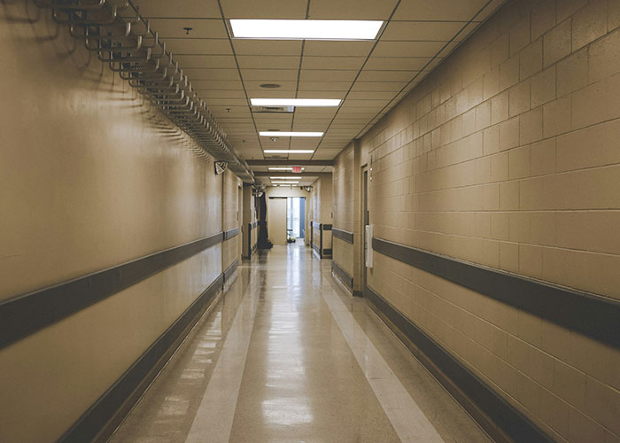 Empty office hallway with beige walls and fluorescent lighting, representing workplace tension. Empty office hallway with beige walls and fluorescent lighting, representing workplace tension.