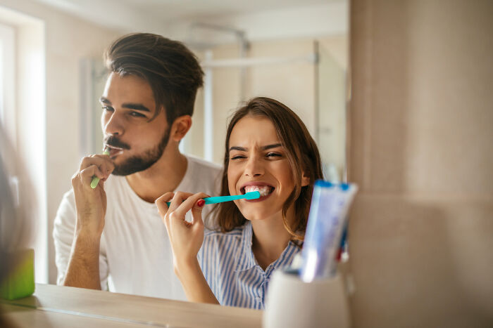 Couple practicing common hygiene habits, brushing teeth together in bathroom.