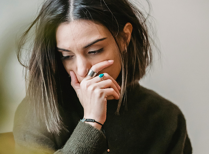 Woman looking concerned, wearing rings and a dark sweater, contemplating after a dispute over "deadbeat mom" remark. Woman looking concerned, wearing rings and a dark sweater, contemplating after a dispute over "deadbeat mom" remark.