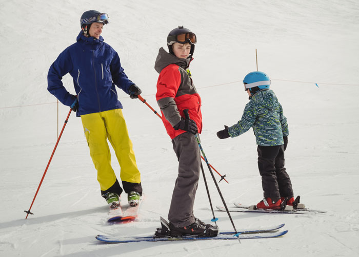 Adult skier with two kids on beginner trail. Adult skier with two kids on beginner trail.