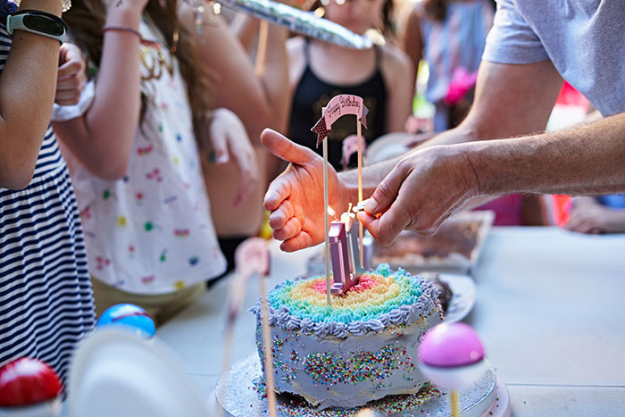 Birthday cake being decorated at a child's party, surrounded by children. Birthday cake being decorated at a child's party, surrounded by children.