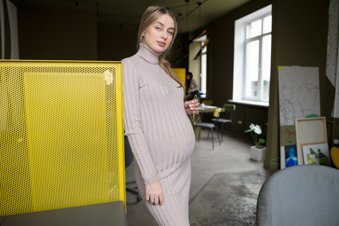 Pregnant teenager indoors, continuing family legacy, wearing beige dress, in modern room with yellow accents. Pregnant teenager indoors, continuing family legacy, wearing beige dress, in modern room with yellow accents.