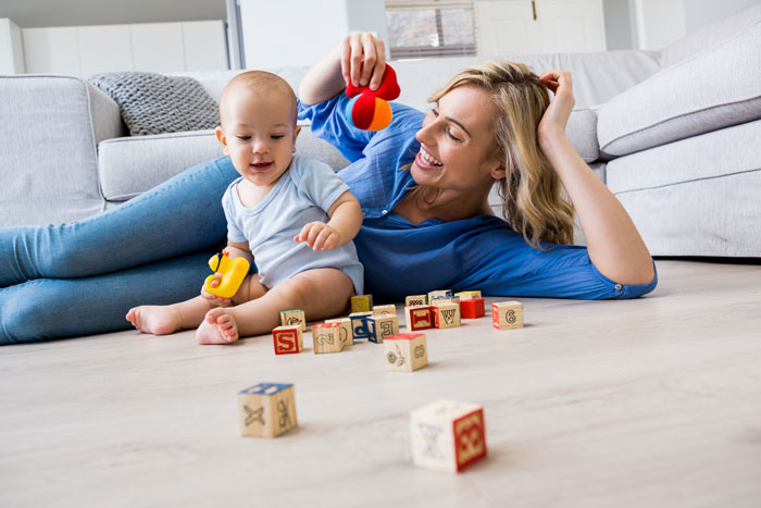 Woman babysitting, playing with a baby on the floor, surrounded by colorful blocks. Woman babysitting, playing with a baby on the floor, surrounded by colorful blocks.