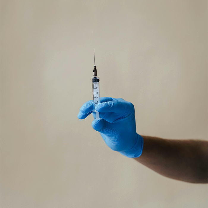 Gloved hand holding a syringe, highlighting Covid vaccines. Gloved hand holding a syringe, highlighting Covid vaccines.