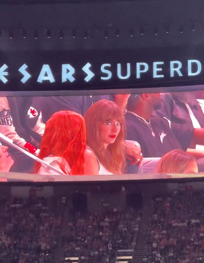 Taylor Swift on stadium screen during Super Bowl, crowd visible below. Taylor Swift on stadium screen during Super Bowl, crowd visible below.