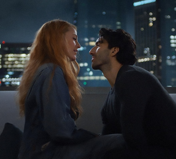 Justin Baldoni and Blake Lively sitting closely on a rooftop at night with a city skyline in the background from 'It Ends With Us'. Justin Baldoni and Blake Lively sitting closely on a rooftop at night with a city skyline in the background from 'It Ends With Us'.
