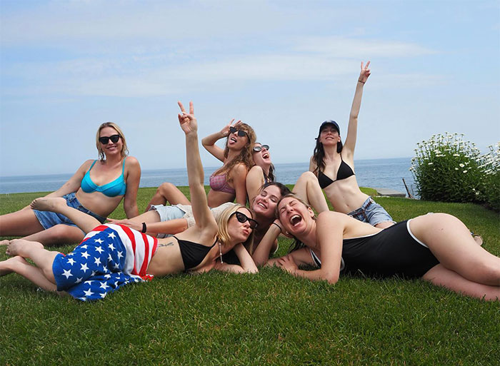 Group of friends smiling and posing on grass by the sea, highlighting pop star lifestyle. Group of friends smiling and posing on grass by the sea, highlighting pop star lifestyle.