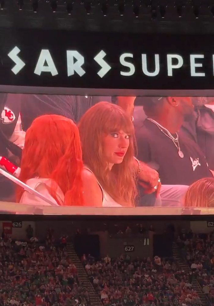 Taylor Swift reacting at the Super Bowl, her image displayed on a large screen above the audience. Taylor Swift reacting at the Super Bowl, her image displayed on a large screen above the audience.