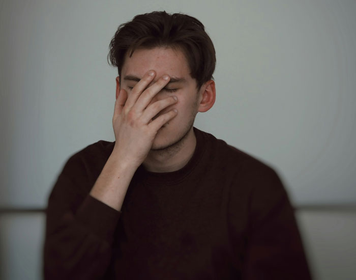 Teen covering face with hand, frustrated about someone using his expensive skincare. Teen covering face with hand, frustrated about someone using his expensive skincare.