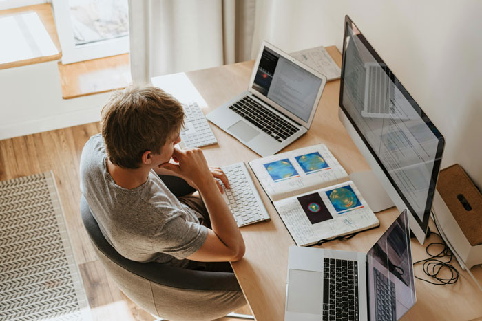 Person at a desk with multiple screens, attempting to optimize company structure and staff. Person at a desk with multiple screens, attempting to optimize company structure and staff.