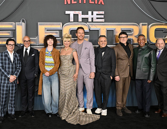 Cast of The Electric State at film premiere, posing together in front of the movie logo. Cast of The Electric State at film premiere, posing together in front of the movie logo.