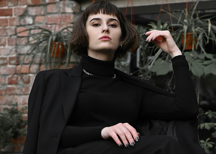 Young woman confidently poses in stylish black suit, symbolizing a reality check moment. Young woman confidently poses in stylish black suit, symbolizing a reality check moment.