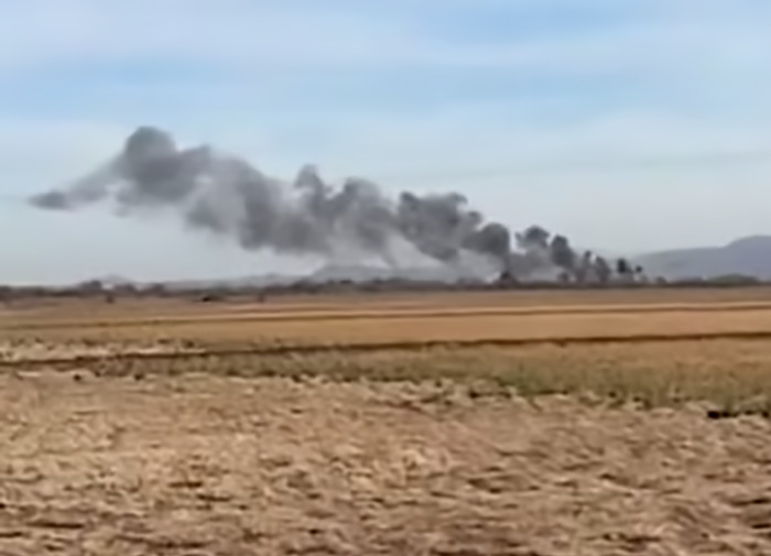 Smoke rising in Arizona field after two planes collide mid-air, with clear skies above. Smoke rising in Arizona field after two planes collide mid-air, with clear skies above.