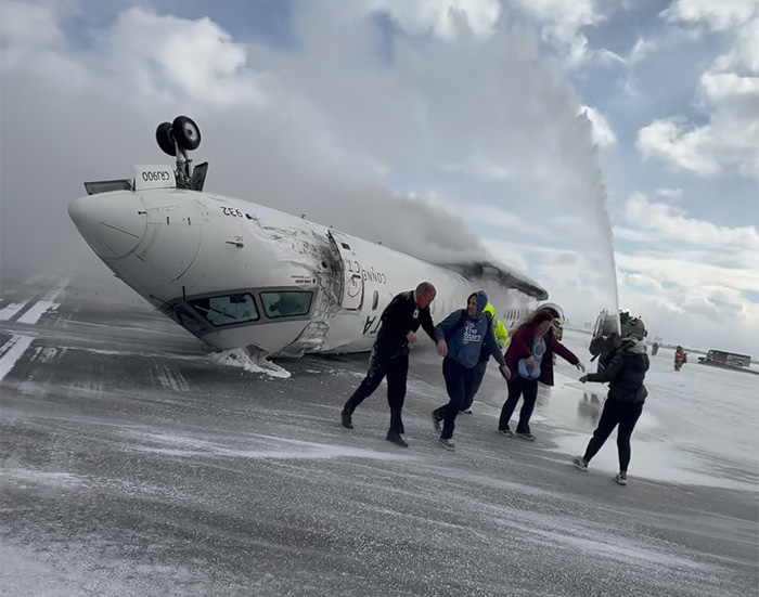 Passengers evacuate after an emergency landing with a plane overturned on the runway, smoke and rescue efforts visible. Passengers evacuate after an emergency landing with a plane overturned on the runway, smoke and rescue efforts visible.