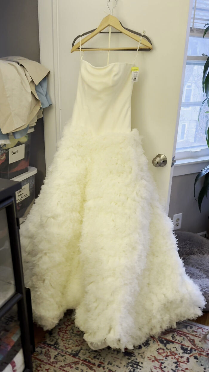 White wedding dress found at thrift store, hanging on a wooden hanger in a room. White wedding dress found at thrift store, hanging on a wooden hanger in a room.